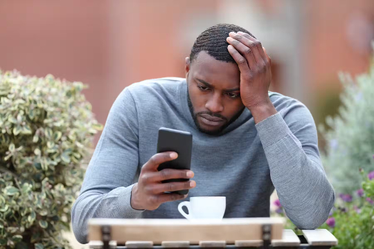 a man apparently very stressed while looking at his phone