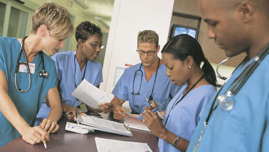 group of healthcare professionals standing around a desk or table