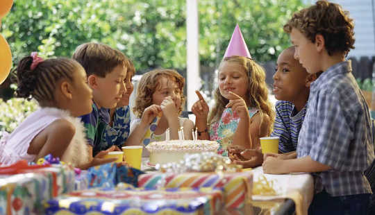 children at a table around a birthday cake