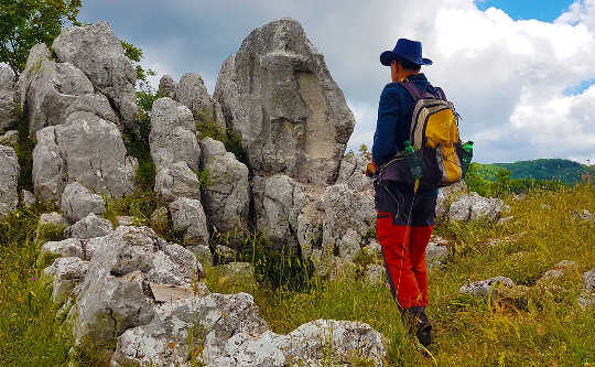 a man with a backpack standing in front of rocks and boulders