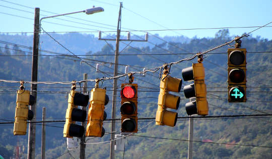 several traffic lights - one red and the other green with two green arrows up and to the righ
