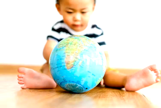 a child sitting on the floor playing with a world globe