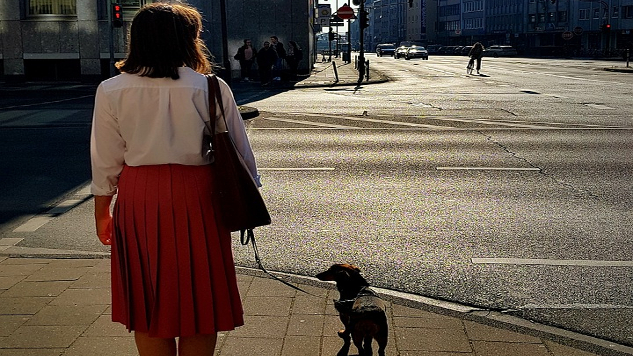a woman with a dog on a mostly empty street