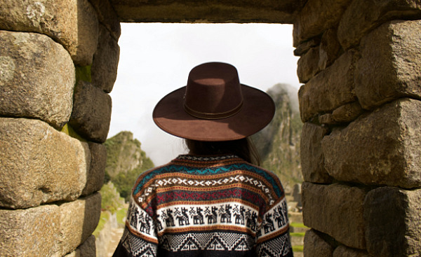 Indian woman standing under a stone arch in Machu Picchu